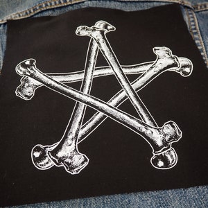 Może przedstawiać: Czarny łata z białym wzorem pięciu skrzyżowanych kości tworzących kształt gwiazdy.