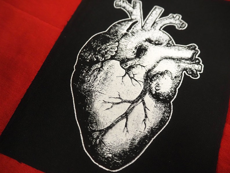 May include: A black and white anatomical heart illustration printed on a black fabric patch. The heart is detailed with veins and arteries.