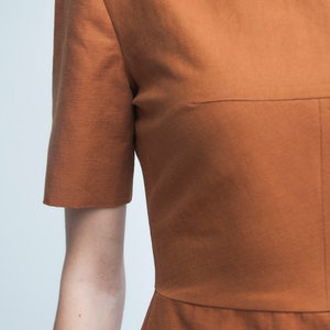 May include: A rust-colored short-sleeved dress with a simple, fitted silhouette.