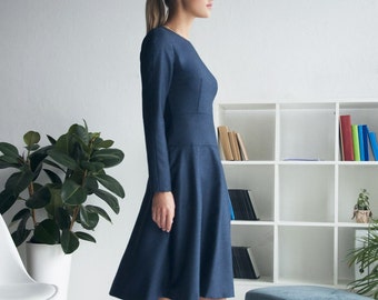 Può includere: Un abito blu navy a maniche lunghe con un corpetto aderente e una gonna svasata. L'abito è realizzato in un tessuto morbido e confortevole e ha un design semplice ed elegante.