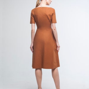 May include: A brown midi dress with a square neckline and short sleeves. The dress has a fitted bodice and a flared skirt.