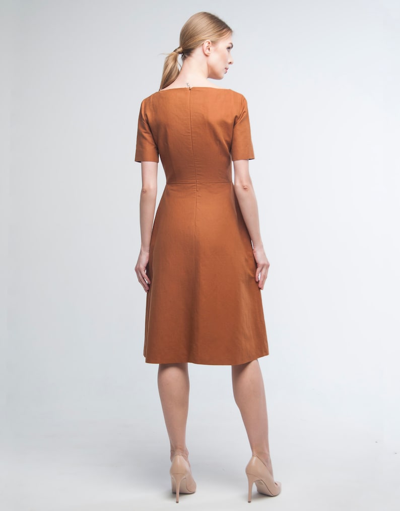 May include: A brown midi dress with a square neckline and short sleeves. The dress has a fitted bodice and a flared skirt.