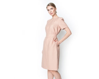 May include: A light pink dress with short sleeves and a fitted waist. The dress has a simple, elegant design.