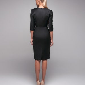 May include: A black midi dress with a fitted silhouette and three-quarter sleeves. The dress has a simple design and is made of a smooth fabric.