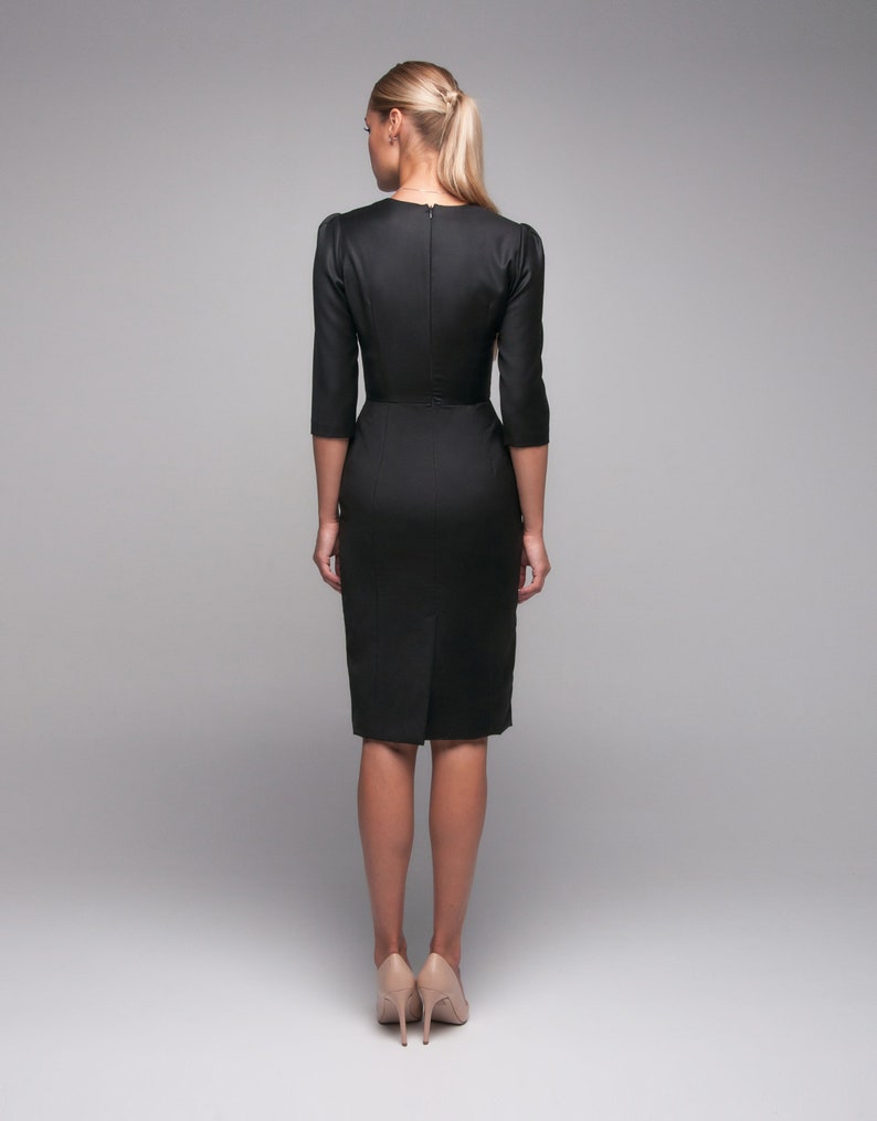 May include: A black midi dress with a fitted silhouette and three-quarter sleeves. The dress has a simple design and is made of a smooth fabric.