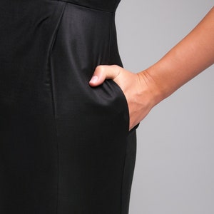 May include: A black dress with a fitted silhouette and a single pocket on the side.