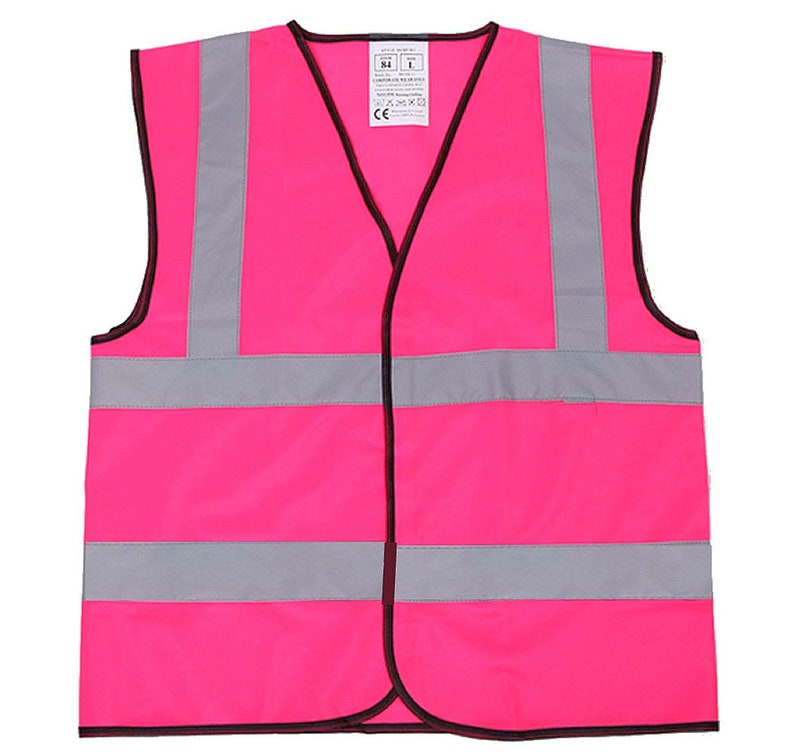 May include: A bright pink safety vest with reflective silver stripes. The vest has a black zipper and a black trim around the edges. The vest has a label with the text "CE" and "M/L".