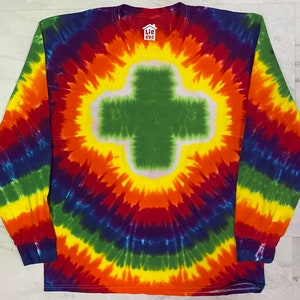 May include: A long-sleeved tie-dye shirt with a rainbow pattern and a green cross in the center. The shirt has a tag that says "tie dye".