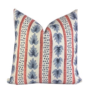May include: A decorative throw pillow with a white background and a pattern of red stripes, blue leaves, and small blue dots.