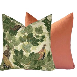 May include: Two decorative throw pillows, one with a green and white pattern of birds and leaves, and the other a solid coral color.