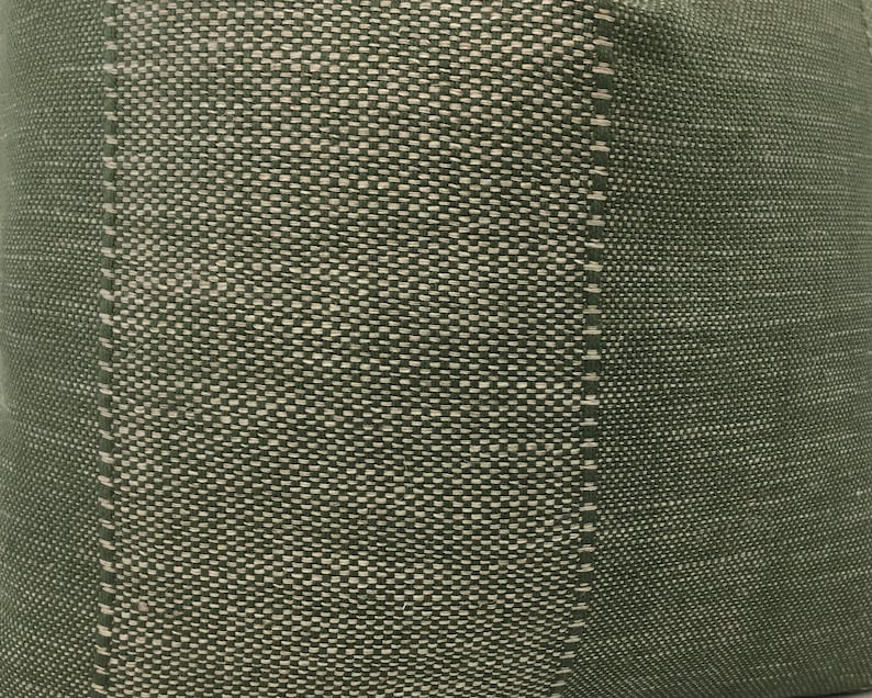 May include: Green fabric with a textured pattern. The fabric has a vertical stripe of a lighter green color.