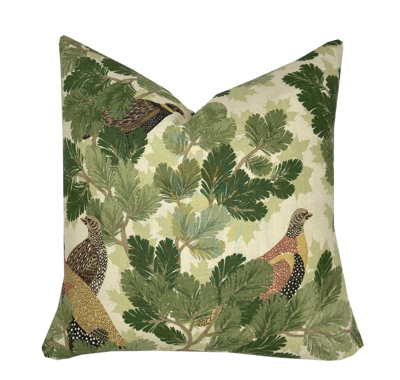 May include: A green and cream throw pillow with a repeating pattern of stylized pine branches and birds. The birds are brown, black, and red with yellow accents.