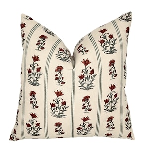 May include: A square throw pillow featuring an off-white base with vertical stripes in a muted green tone. The fabric is decorated with a repeating pattern of small, dark red floral motifs arranged in columns between the vertical striped lines.