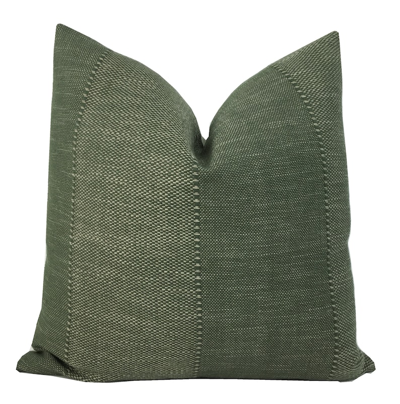 May include: A green throw pillow with a textured woven fabric. The pillow has a subtle white pattern throughout the fabric.