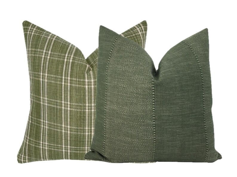 May include: Two green throw pillows, one with a plaid pattern and the other with a textured weave.
