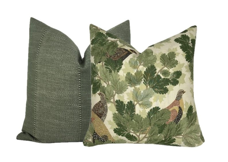 May include: Two decorative throw pillows. One pillow is green with a subtle textured pattern. The other pillow is white with a green and brown pattern of leaves and birds.