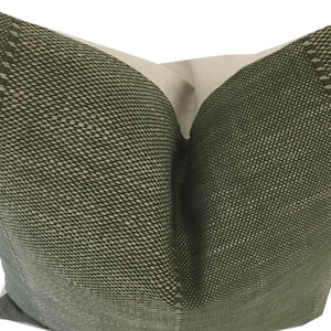 May include: A green pillow with a subtle textured pattern. The pillow is made of a soft, woven fabric and has a simple, elegant design.