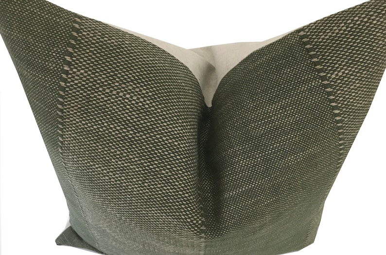 May include: A green pillow with a subtle textured pattern. The pillow is made of a soft, woven fabric and has a simple, elegant design.