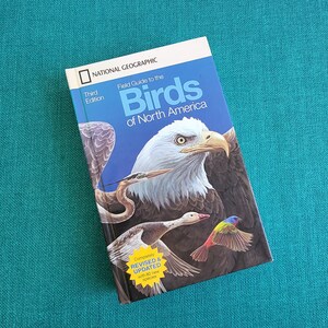 May include: A National Geographic field guide to the birds of North America, third edition, with a cover featuring a bald eagle, a great blue heron, a duck, and a painted bunting.