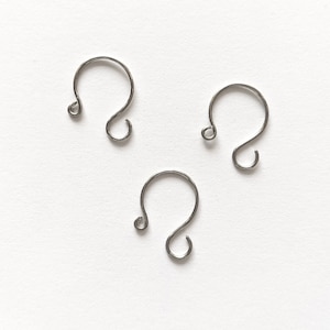 May include: Three silver-colored, open-circle earring hooks with a looped end. The hooks are arranged on a white background. The hooks are made of a thin, wire-like material.