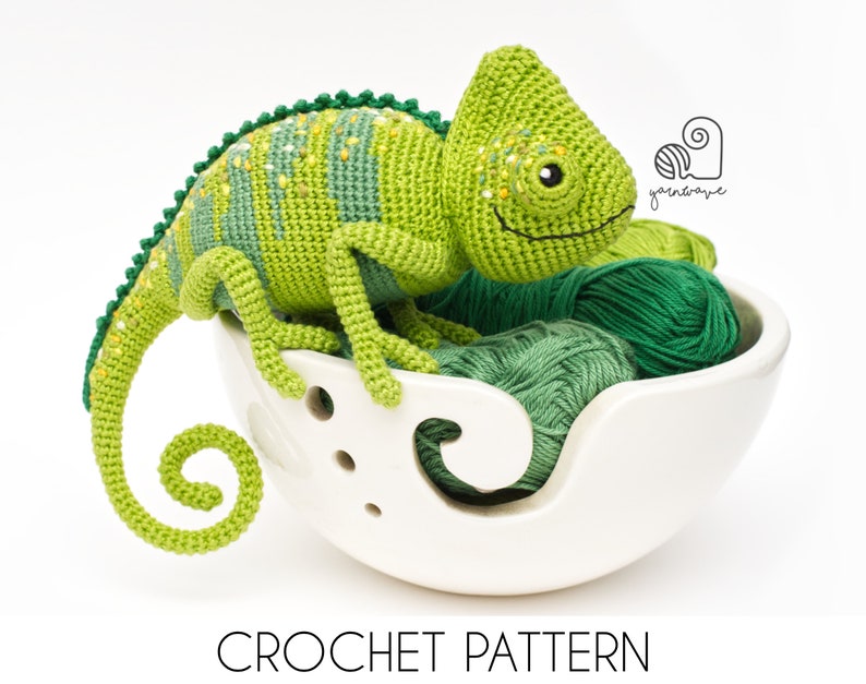 Puede incluir: Juguete de amigurumi de camale&oacute;n verde tejido a crochet sentado en un bol de lana blanco con lana verde. Patr&oacute;n de crochet.