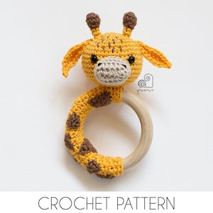 May include: Crocheted giraffe rattle toy with a wooden ring. The giraffe is yellow with brown spots and has black eyes. The rattle is a great baby toy.