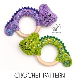 May include: Two crocheted chameleon baby rattles with wooden rings. One is purple and the other is green.