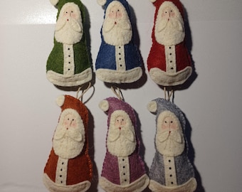 May include: Six handmade Santa Claus ornaments in various colors: green, blue, red, orange, purple, and gray. Each ornament features a white beard, face, and trim, with a buttoned coat and a loop for hanging. Festive holiday decor.