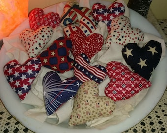 May include: A white bowl filled with red, white, and blue fabric hearts. The hearts are decorated with stars and other patriotic patterns.