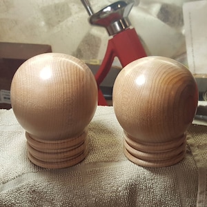 May include: Two wooden spheres with a smooth, polished finish. Each sphere is mounted on a base with a series of rings.