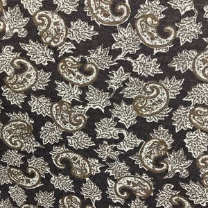 May include: A dark brown fabric with a white paisley pattern. The pattern features intricate swirls and leaves.