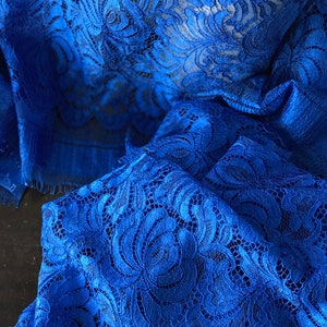 May include: Royal blue lace fabric with a delicate floral pattern. The lace is soft and flowing, making it perfect for a variety of projects.