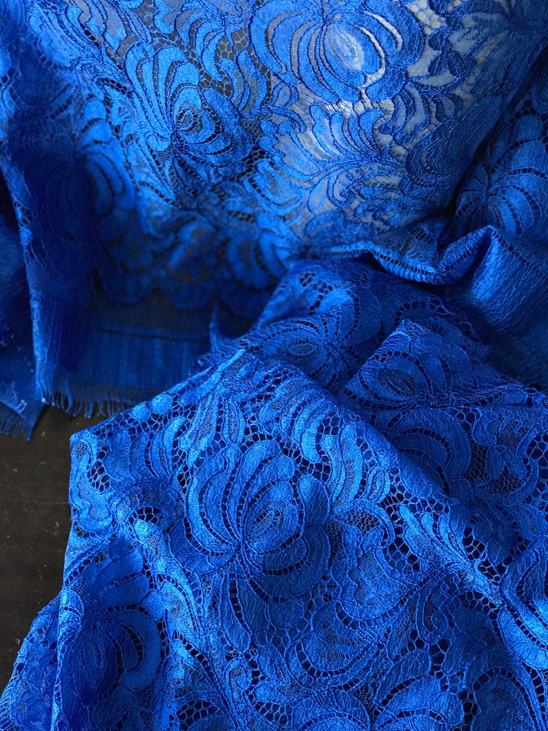 May include: Royal blue lace fabric with a delicate floral pattern. The lace is soft and flowing, making it perfect for a variety of projects.