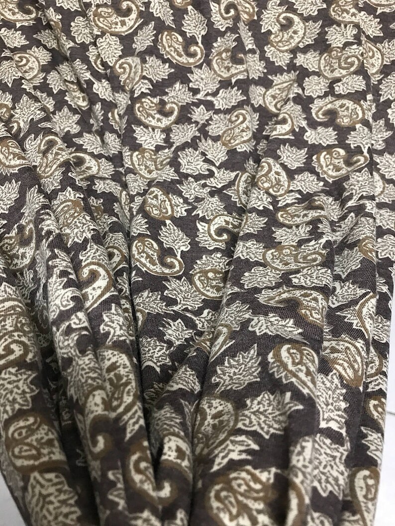 May include: Brown fabric with a paisley and leaf pattern in beige and brown.