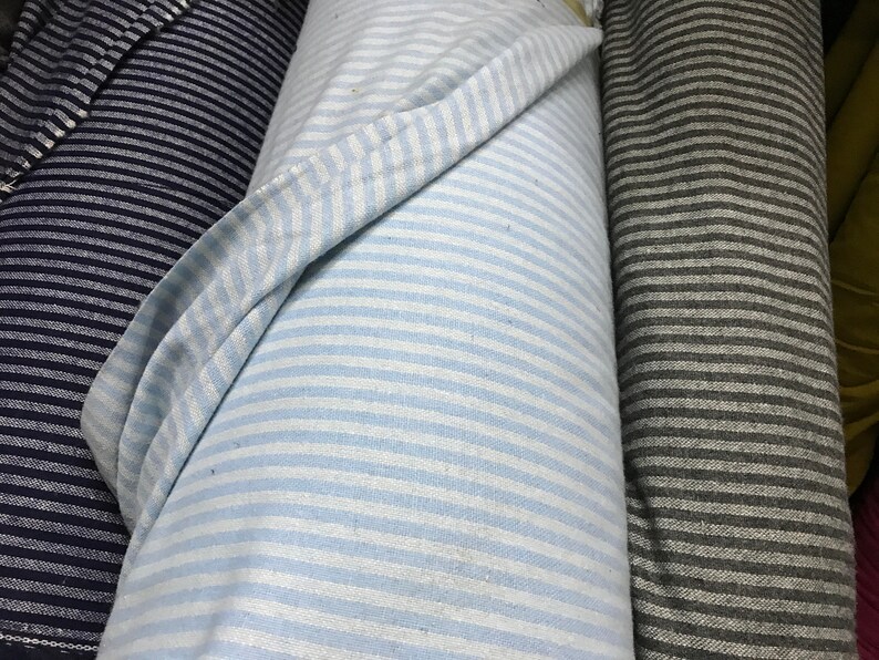 May include: Three rolls of striped fabric. One roll is navy blue and white, one is light blue and white, and one is gray and white.