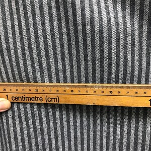 May include: Close-up of a black and white striped fabric with a ruler measuring 39 centimeters. The ruler reads "1 centimeter (cm)".