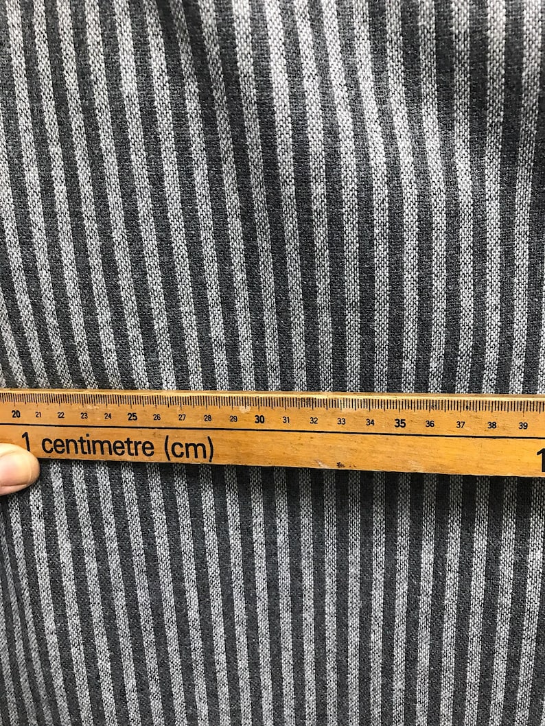 May include: Close-up of a black and white striped fabric with a ruler measuring 39 centimeters. The ruler reads "1 centimeter (cm)".