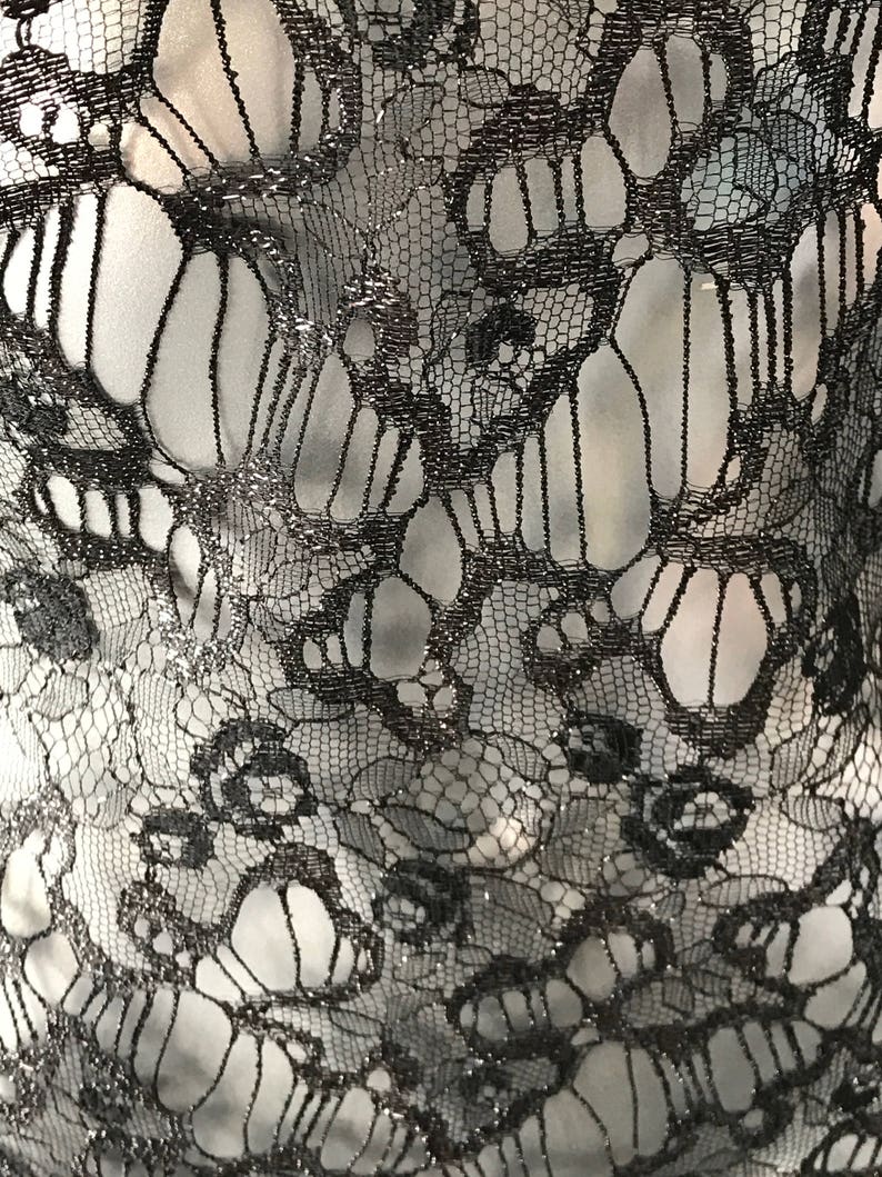 May include: Black lace fabric with a delicate floral pattern. The lace has a subtle shimmer.