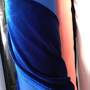 May include: A roll of royal blue velvet fabric. The fabric is folded and draped, showing the soft texture and rich color.