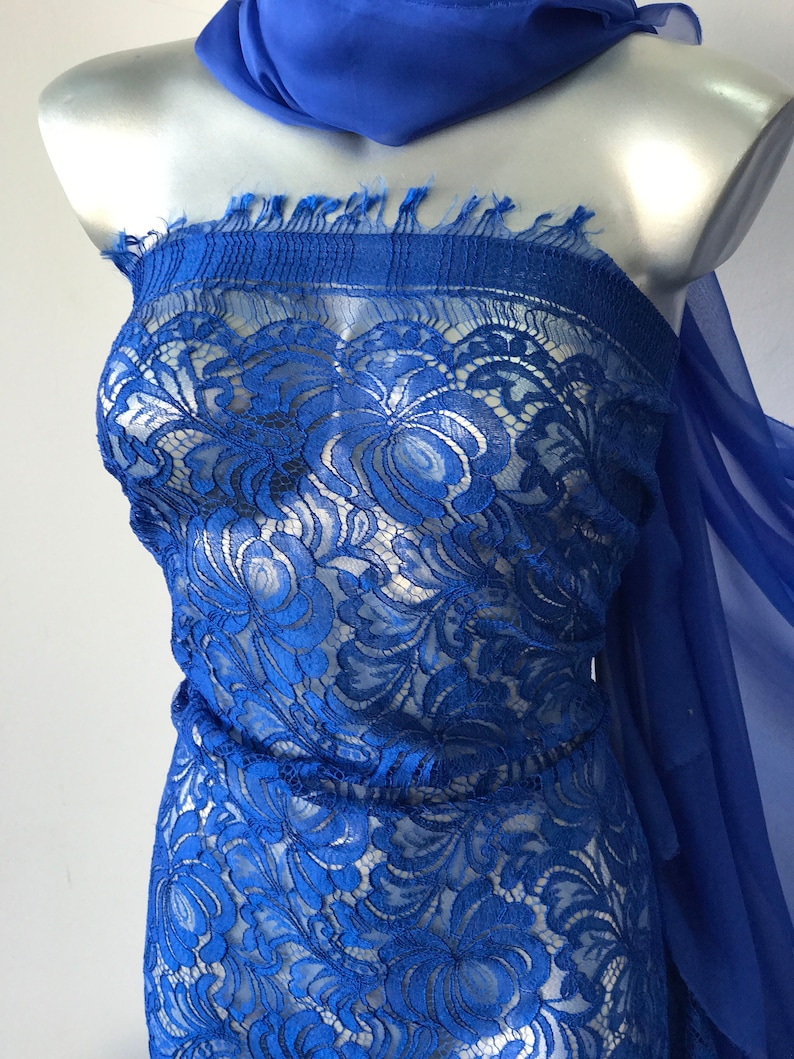 May include: Royal blue lace fabric with a floral pattern. The lace is delicate and sheer, and it would be perfect for a variety of projects, such as dresses, tops, and skirts.