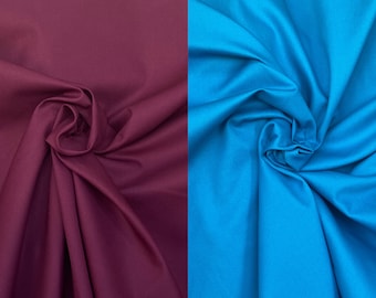 May include: Two sections of fabric, one a deep burgundy and the other a vibrant turquoise blue, are artfully draped and folded. The textures of the textiles are smooth and reflect light. The words "Bodikian Textiles" are printed in white on the lower right corner.