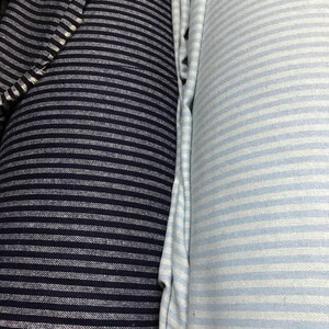 May include: Two rolls of striped fabric, one navy blue and white, and the other light blue and white.