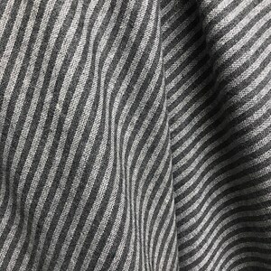May include: A close-up of a gray and white striped fabric with a wavy pattern.