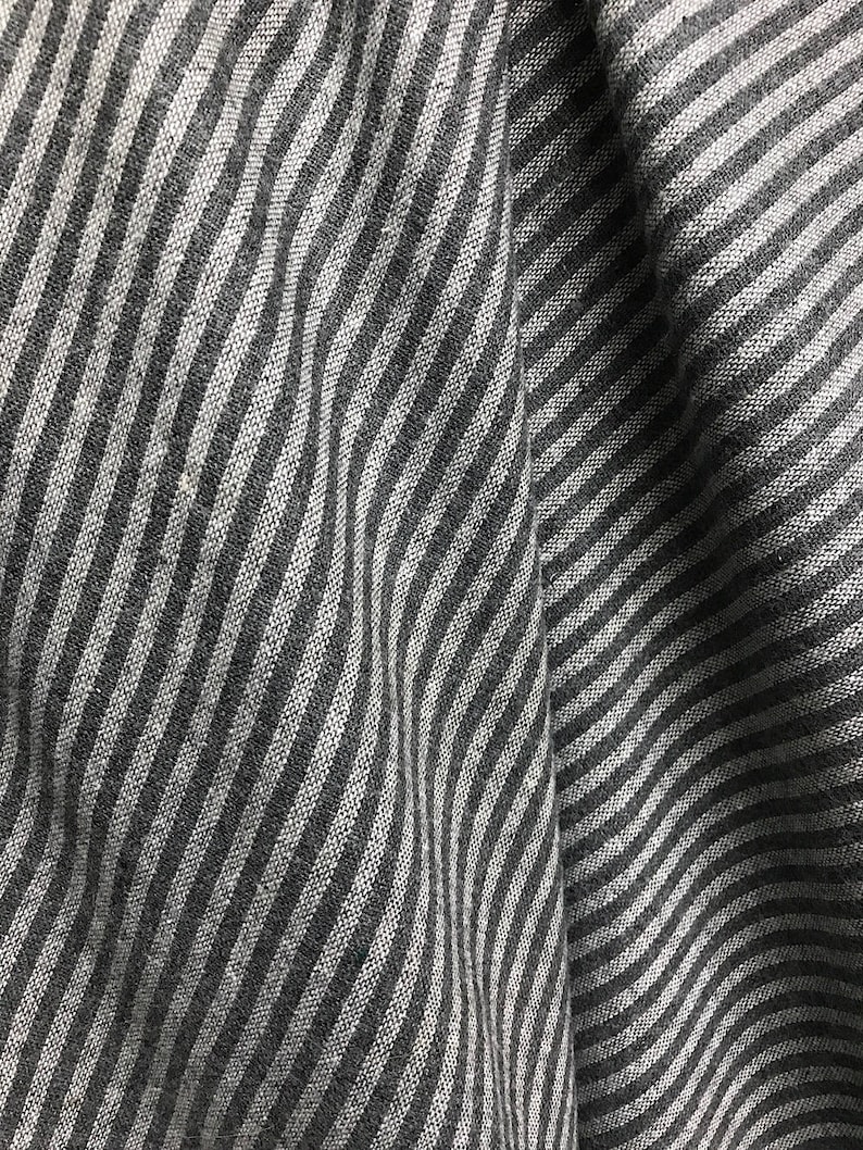 May include: A close-up of a gray and white striped fabric with a wavy pattern.