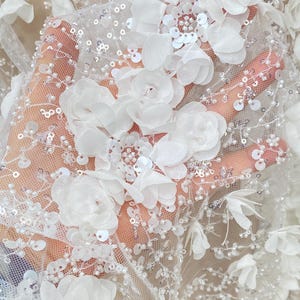 Peut inclure: Tissu de dentelle florale blanche avec des embellissements de fleurs 3D et des paillettes.
