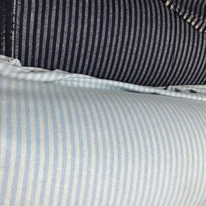May include: Two rolls of striped fabric. The top roll is dark blue with white stripes. The bottom roll is light blue with white stripes.