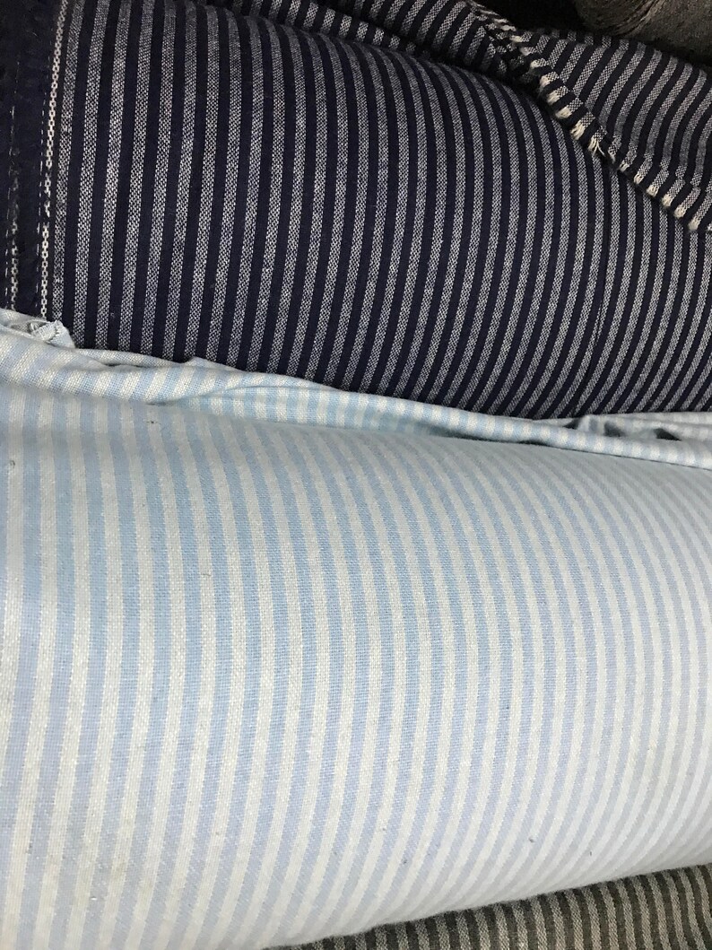 May include: Two rolls of striped fabric. The top roll is dark blue with white stripes. The bottom roll is light blue with white stripes.