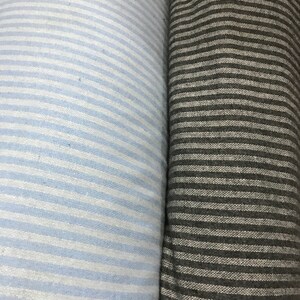 May include: Two rolls of striped fabric, one light blue and white, the other dark gray and white.