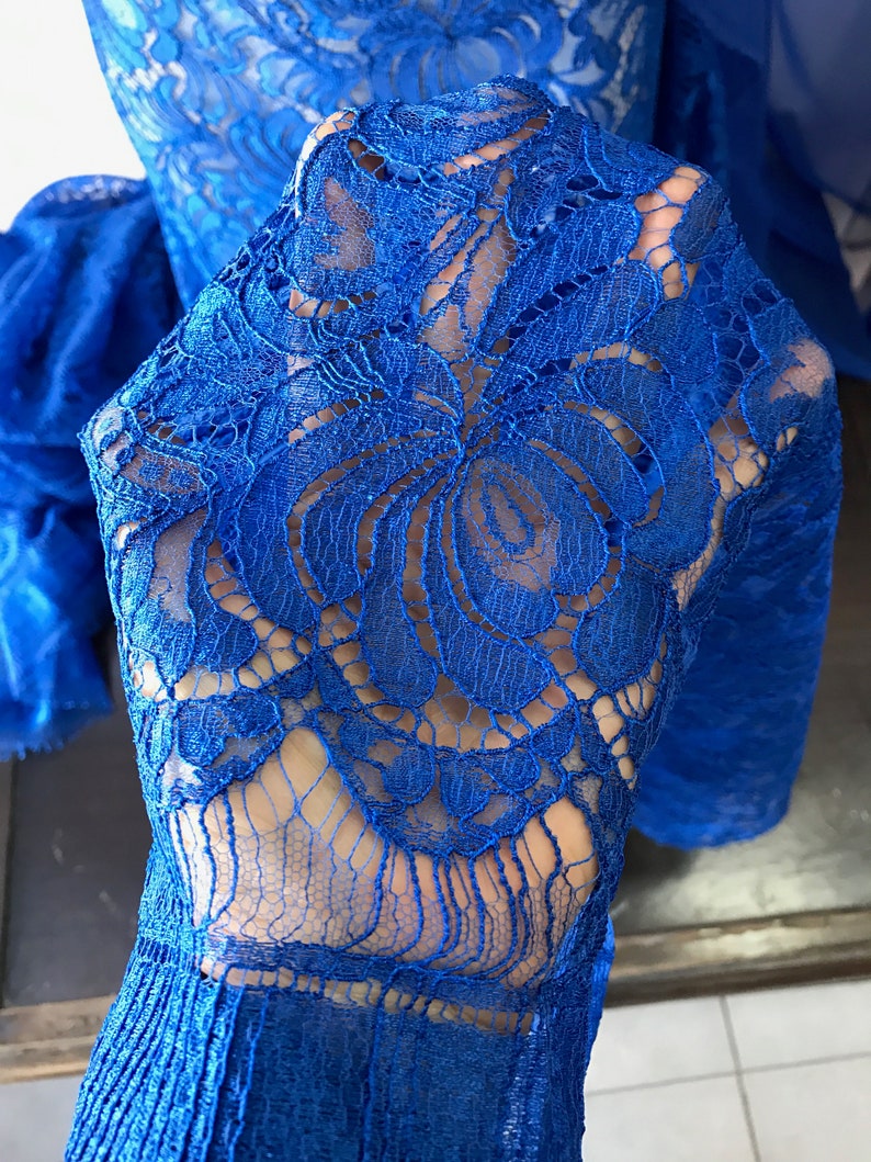 May include: Royal blue lace fabric with a floral pattern. The lace is delicate and intricate, with a soft, flowing texture.