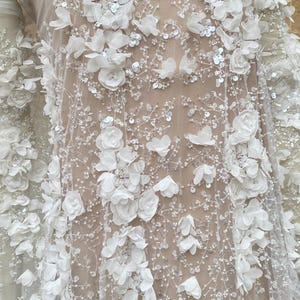 Peut inclure: Tissu de dentelle florale blanche avec des fleurs 3D et des paillettes. Le tissu est transparent et d&eacute;licat, avec une sensation douce et romantique.